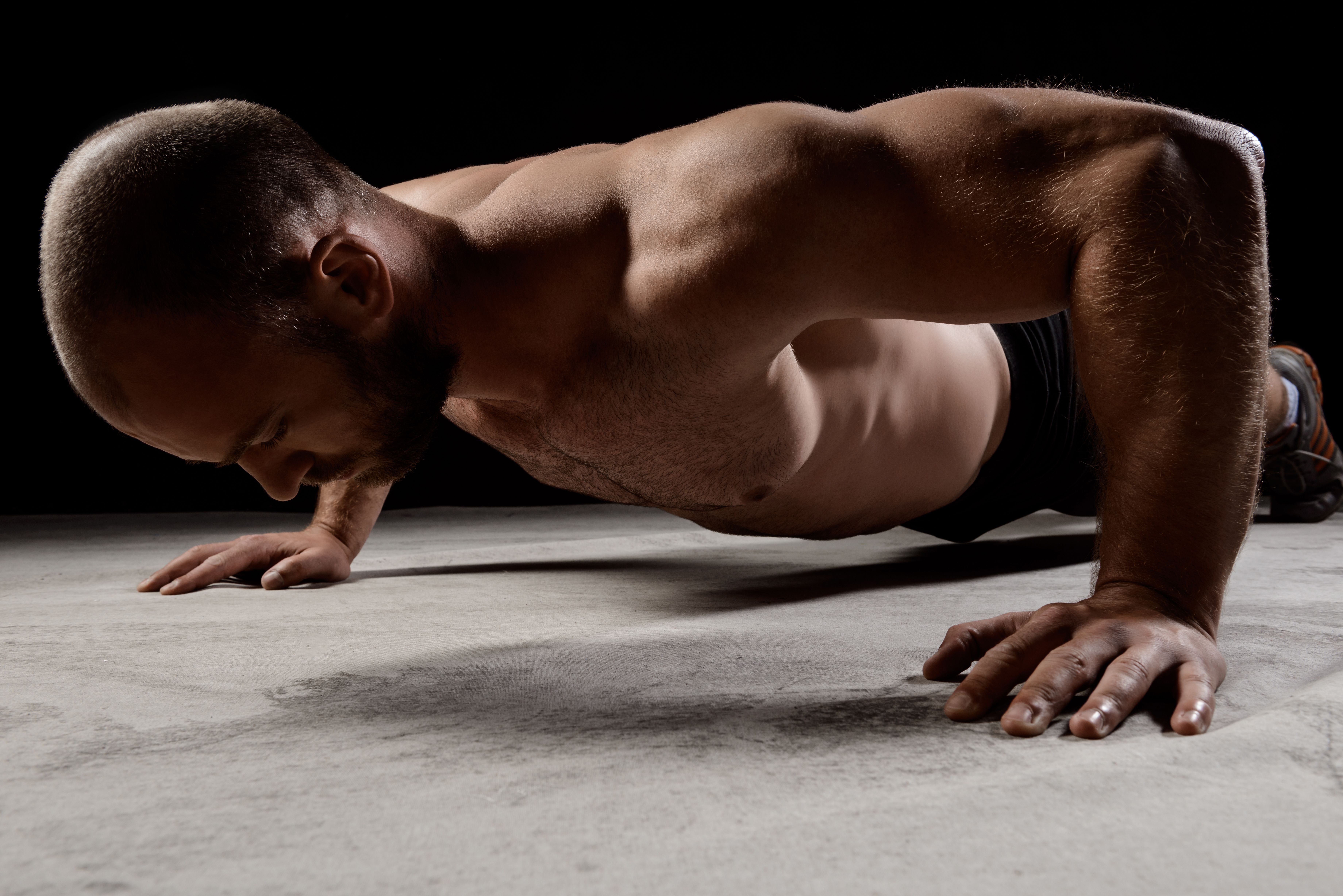 young-powerful-sportsman-training-push-ups-dark-wall (1).jpg