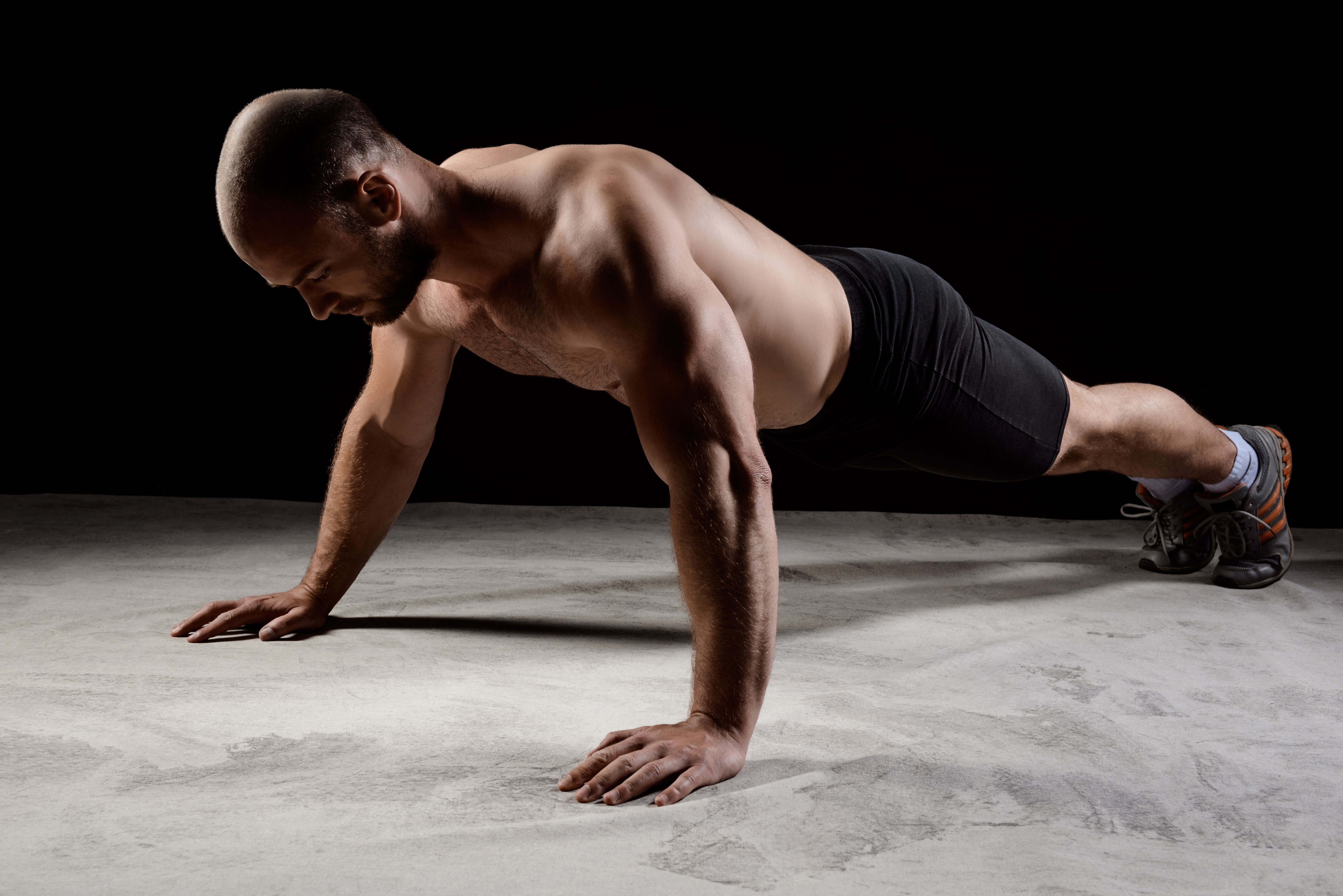 young-powerful-sportsman-training-push-ups-dark-wall.jpg